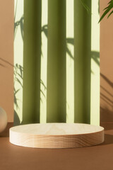 Wooden podium on an abstract green and beige background with the shadow of palm leaves. Empty scene with a geometric backdrop for the product presentation. Showcase for natural eco cosmetic.