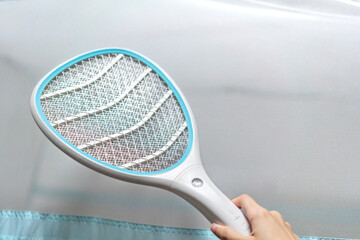 Chikungunya concept with electric mosquito swatter outside mosquito net