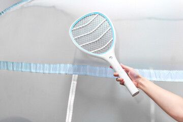 Chikungunya concept with electric mosquito swatter outside mosquito net