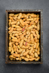 Wooden box filled with unshelled peanuts. On a gray concrete background. Nuts Close-up.