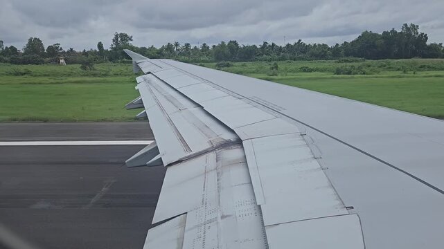 View from airplane window showing wing and extended flaps as the aircraft taxis on the runway before takeoff at Can Tho Airport, Vietnam.