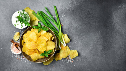 Crispy Potato chips with sour cream, onion and greens flavor in a ceramic bowl. Salty snacks.