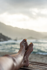 Fototapeta premium Legs of woman relaxing on the beach enjoying the sunset in tayrona park, colombia