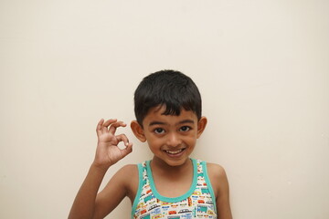a cute indian asian boy of 5 years with gorgeous eyes and jovial facial expression in light background