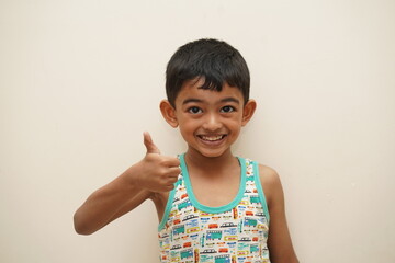 a cute indian asian boy of 5 years with gorgeous eyes and jovial facial expression in light background