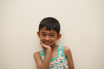 a cute indian asian boy of 5 years with gorgeous eyes and jovial facial expression in light background