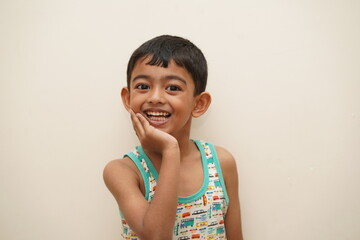 a cute indian asian boy of 5 years with gorgeous eyes and jovial facial expression in light background