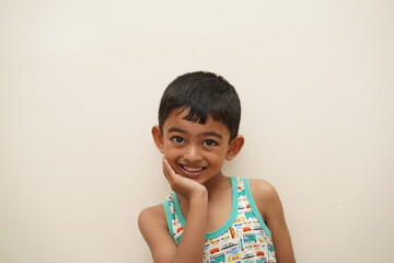 a cute indian asian boy of 5 years with gorgeous eyes and jovial facial expression in light...