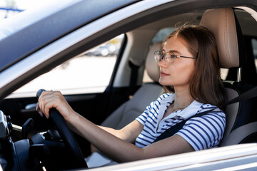Young office worker driving modern car wearing eyeglasses