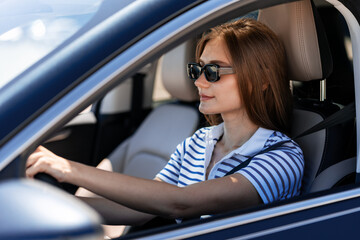 Young woman driving a modern car wearing sunglasses