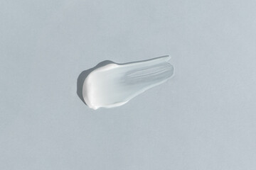 White cream texture on a light gray background. A smear of a cosmetic skin care product. Wellness and beauty concept.