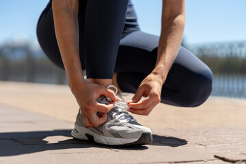 Woman tying running shoes laces getting ready for jogging outdoors