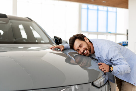 Happy customer hugging his new car in the dealership