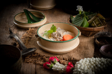 Pork congee, Thai desserts and jasmine flowers are placed on the dining table. Retro Thai style image.