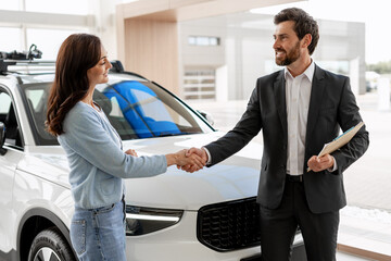 Car salesman shaking hands with customer in dealership after successful deal