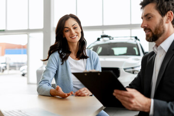 Salesman showing contract to customer buying new car in dealership