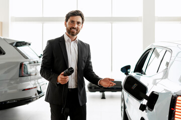 Car dealer showing charging connector of electric vehicle in showroom