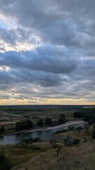 A Serene Landscape Featuring a Meandering River Surrounded by Dramatic, Colorful Clouds