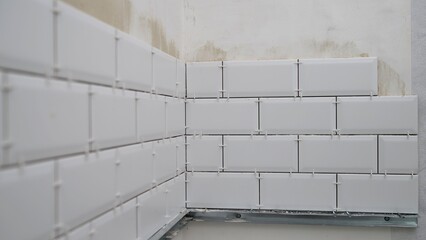 Professional builder carefully protecting pristine white ceramic tiles with precision masking tape during detailed home renovation process