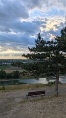 A Serene and Beautiful Landscape Featuring a Bench Overlooking a Picturesque River and Rolling Hills