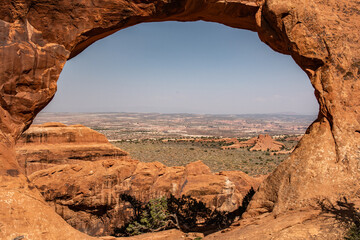 A scenic view of the landscape through a natural rock arch, showcasing the beauty of nature and...