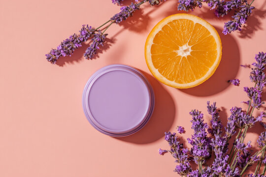 A slice of orange and a purple jar are surrounded by lavender sprigs