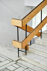 A flight of stairs with marble steps. Whitewashed walls and wooden staircase railings. The staircase of an old building.
