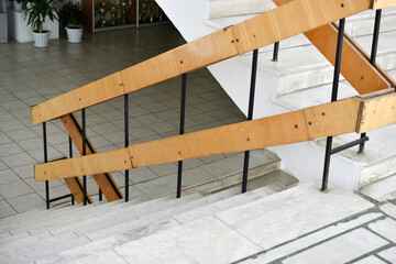 A flight of stairs with marble steps. Whitewashed walls and wooden staircase railings. The staircase of an old building.