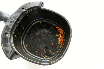 Dirty grunge air fryer with chips and food leftovers.