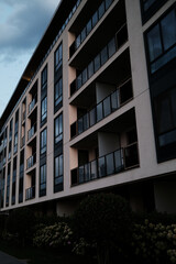 Fototapeta premium Modern residential building with glass balconies in the Belgrade Waterfront district, Serbia. Urban architecture with evening light and landscaped greenery.