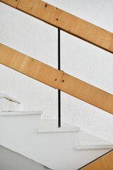 A flight of stairs with marble steps. Whitewashed walls and wooden staircase railings. The staircase of an old building.