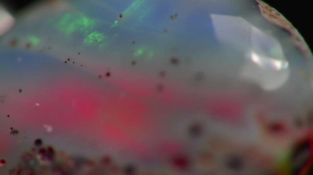 Iridescent opal gemstone macro shot, colorful precious mineral with red and green fire, abstract crystal texture background