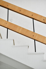A flight of stairs with marble steps. Whitewashed walls and wooden staircase railings. The staircase of an old building.