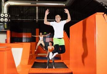 Cheerful young man in sportswear enjoying high jump, surrounded by bright colorful setting of...