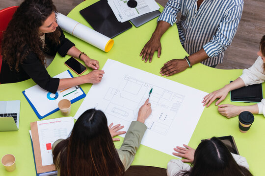 Businesswoman explaining floor plan to colleagues on table