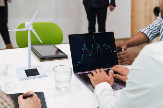 Businessman using laptop with line graph on screen during a meeting in office