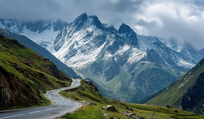 Snow-capped peaks and winding road through green valleys in the French Alps, with dramatic overcast skies and a lone car evoking adventure