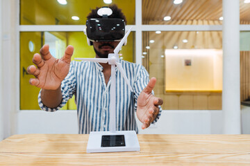 Engineer with wind turbine model on table in office wearing VR goggles