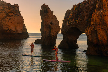 Magnificent view of Ponta da Piedade with two stand-up paddlers at sunrise in Lagos