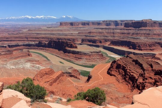 Vast canyon landscape, winding river, red rock formations, distant mountains