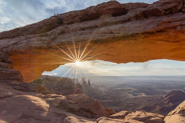 The sun shines through Mesa Arch in Canyonlands National Park, Utah, creating a stunning natural...
