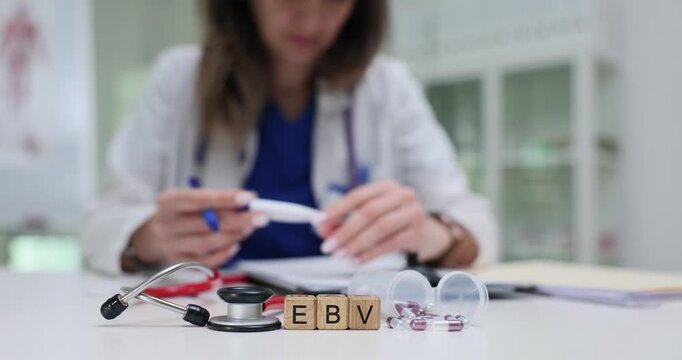 Wooden cubes display EBV near stethoscope and pills suggesting viral nature. Light in office creating clean atmosphere around diagnostic doctor table