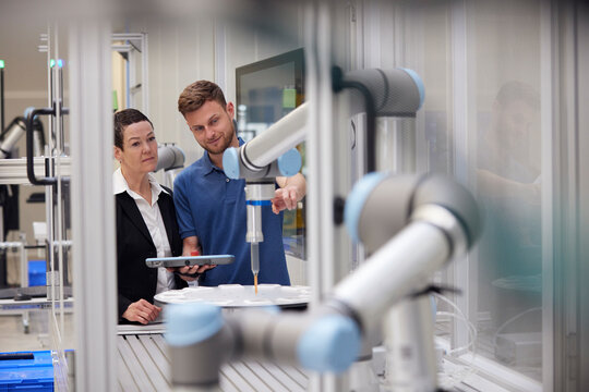 Engineer explaining robotic arm to manager in industry