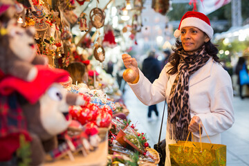 Latino woman with a Christmas tree toy in her hand buys decorations for new year