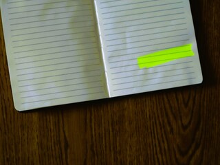 Notebook with blank bright highlights for text message, on a wooden table background