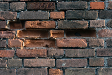 stone wall of orange colored stones where stones are missing