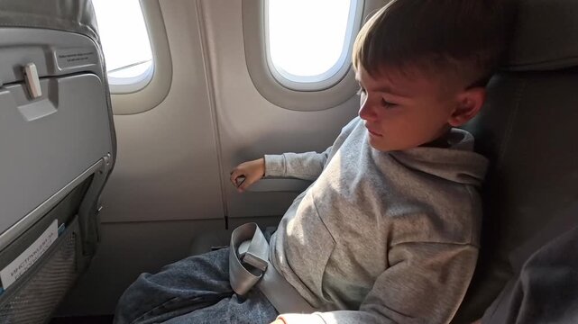 Close-up view of a child covering his face and crying.Headache in the airplane, kid passenger afraid and feeling bad during the flight in plane