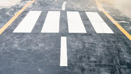 Classic white crosswalk lines on black asphalt with a clear central marker and subtle yellow...