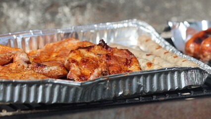 Grilled meat selection on a foil tray, ready for a barbecue or outdoor feast