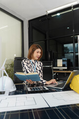 Architect woman working with blueprints for sketching a construction project, green energy and...